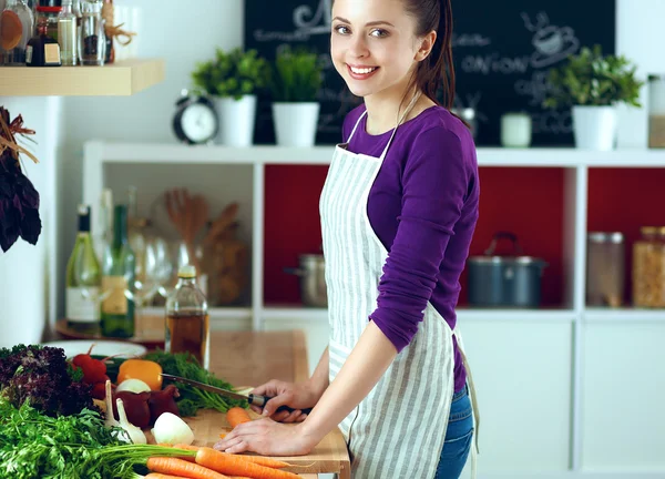 Jovem mulher cortando legumes na cozinha — Fotografia de Stock