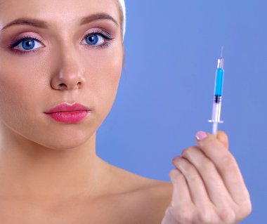 Onun elinde şırınga ile genç güzel kadın. Gri arka plan üzerinde izole
