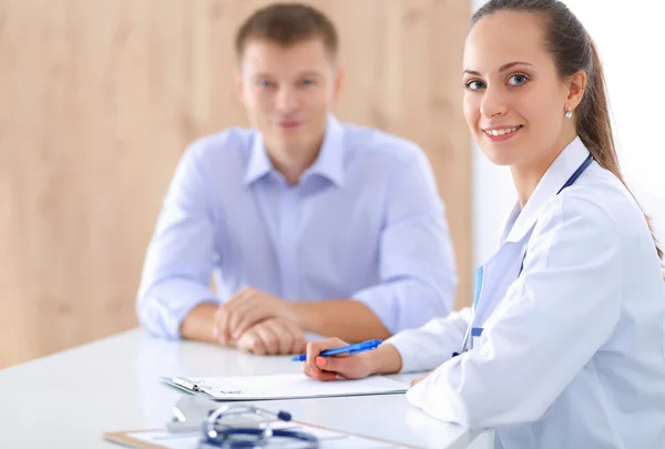 Médecin femme assise avec un patient masculin au bureau — Photo