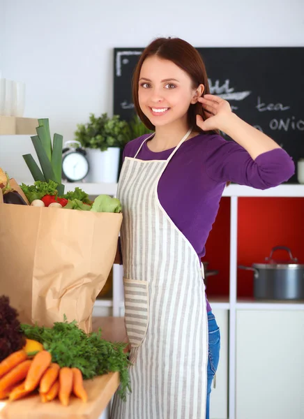 Mujer joven de pie en su cocina cerca del escritorio — Foto de Stock