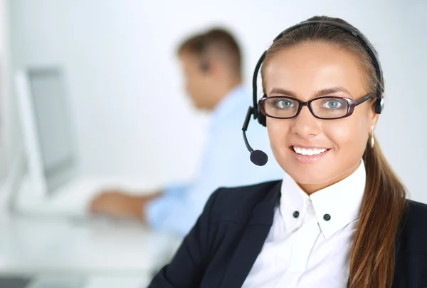 Gelukkig vrouwtje draagt een headset en zit op het bureau — Stockfoto