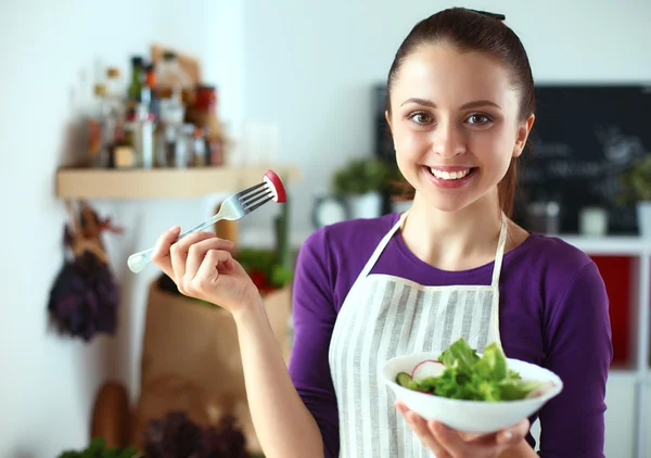 Mujer joven comiendo ensalada fresca en la cocina moderna — Foto de Stock