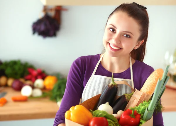 Young woman holding grocery shopping bag with vegetables Standing in the kitchen — Stock Photo, Image