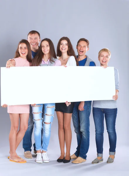 Happy young group of people standing together and holding a blank — Stock Photo, Image