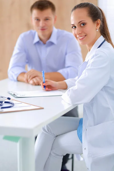 Ärztin sitzt mit männlichem Patienten am Schreibtisch — Stockfoto