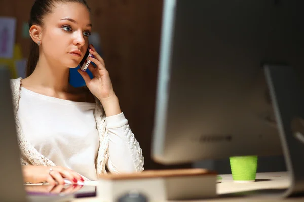 Junge Frau arbeitet im Büro, sitzt am Schreibtisch und telefoniert — Stockfoto
