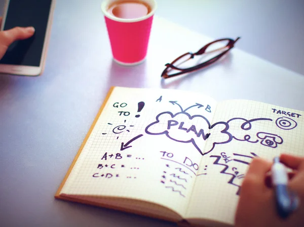 Young woman writes to diary on a white table — Stock Photo, Image