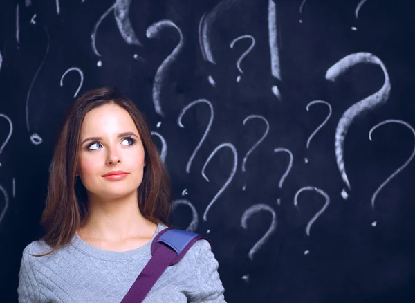 Chica joven con signo de interrogación sobre un fondo gris — Foto de Stock