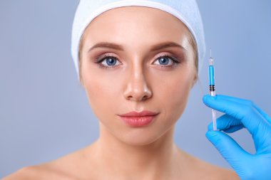 Güzel kadın yüz kozmetik enjeksiyon. Gri arka plan üzerinde izole