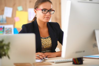 Moda tasarımcıları stüdyoda çalışıyor. Masanın üzerinde oturuyorlar.