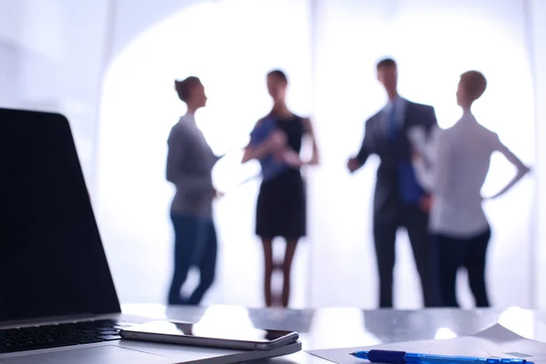 Laptop  computer on  desk ,  businesspeople standing in the background — Stock Photo, Image