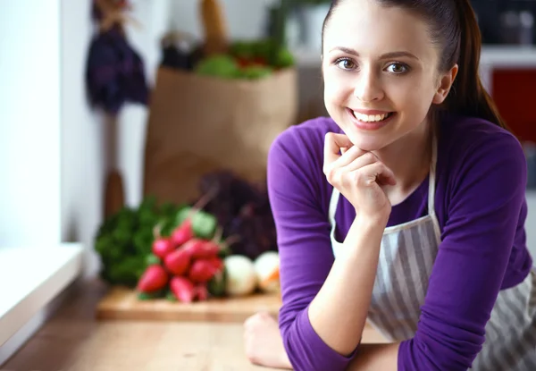 Young woman standing in her kitchen near desk — Stock Photo, Image