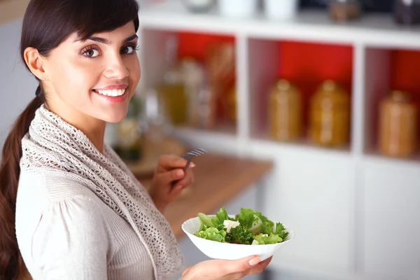 Young woman eating fresh salad in modern kitchen — Stock Photo, Image