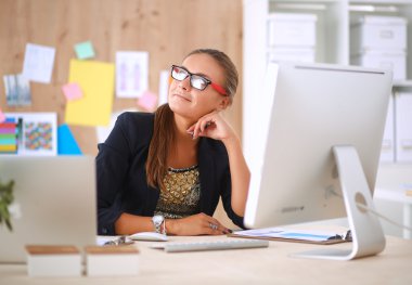 Moda tasarımcıları stüdyoda çalışıyor. Masanın üzerinde oturuyorlar.