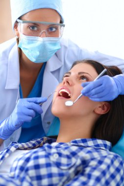 Kadın dişçi hastalarının dişlerinde çalışıyor.