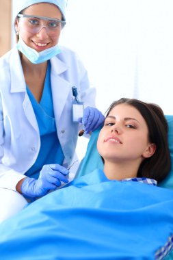 Kadın dişçi hastalarının dişlerinde çalışıyor.