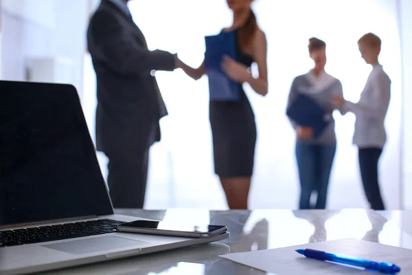 Laptop auf dem Schreibtisch, Geschäftsleute im Hintergrund — Stockfoto