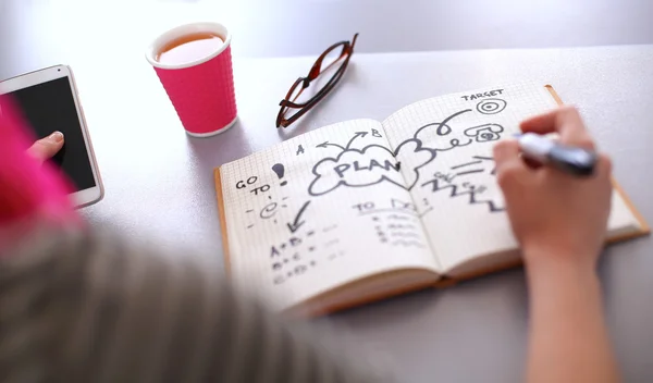 Jonge vrouw schrijft naar dagboek op een witte tabel — Stockfoto