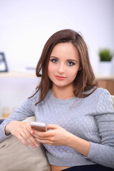 Hübsches Mädchen mit ihrem Smartphone auf der heimischen Couch im Wohnzimmer — Stockfoto