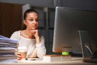 Ofiste çalışan genç bir kadın, masada oturuyor.