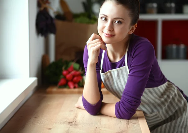 Jovem mulher de pé em sua cozinha perto da mesa — Fotografia de Stock