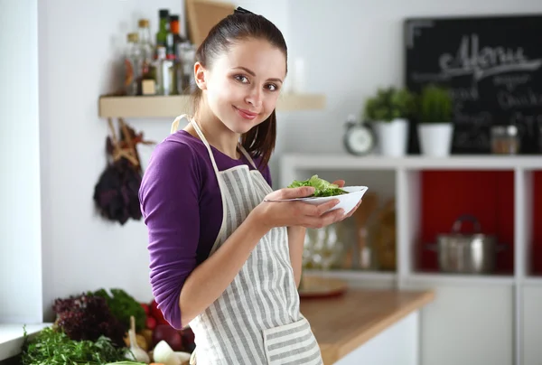 Jonge vrouw die verse salade eet in de moderne keuken — Stockfoto