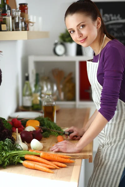 Junge Frau schneidet Gemüse in der Küche — Stockfoto