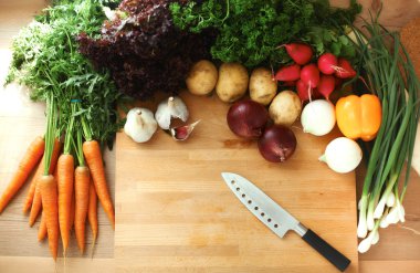 Mutfaktaki masanın üstünde sebzeler var.