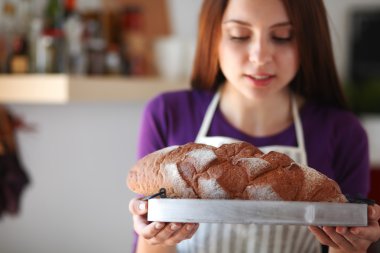 Genç bir kadın mutfağında lezzetli taze ekmek tutuyor.