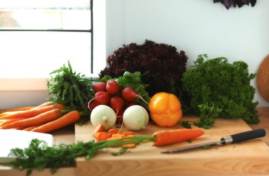 Mutfaktaki masanın üstünde sebzeler var.