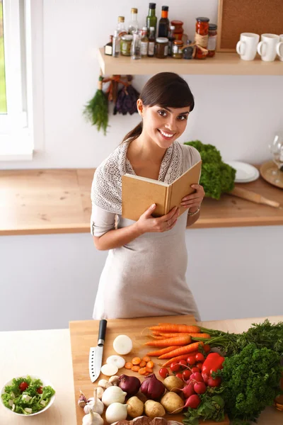 주방에서 요리 책을 읽고 있는 젊은 여자가 요리법을 찾고 있다 — 스톡 사진