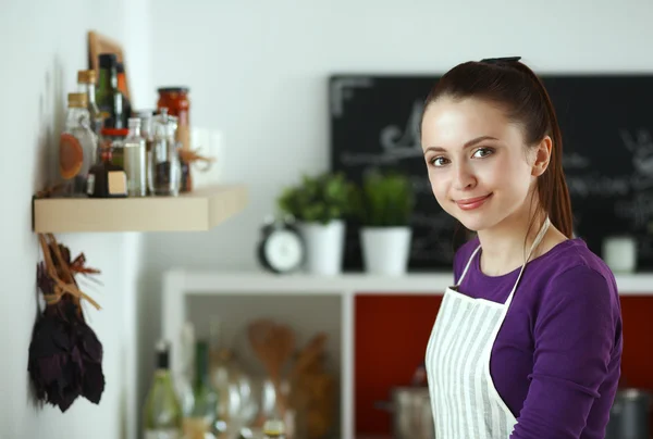 Ung kvinna som står i hennes kök nära skrivbord med kassar och påsar — Stockfoto