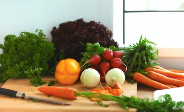 Mutfaktaki masanın üstünde sebzeler var.