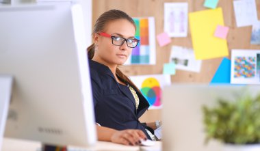 Moda tasarımcıları stüdyoda çalışıyor. Masanın üzerinde oturuyorlar.