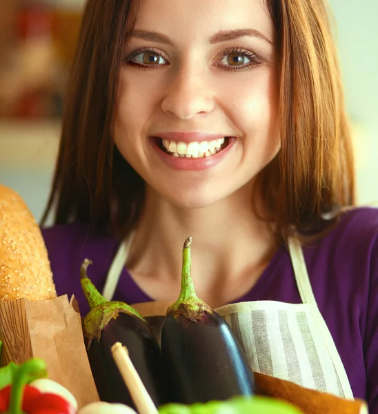 Jonge vrouw met boodschappentas met groenten Staande in de keuken — Stockfoto