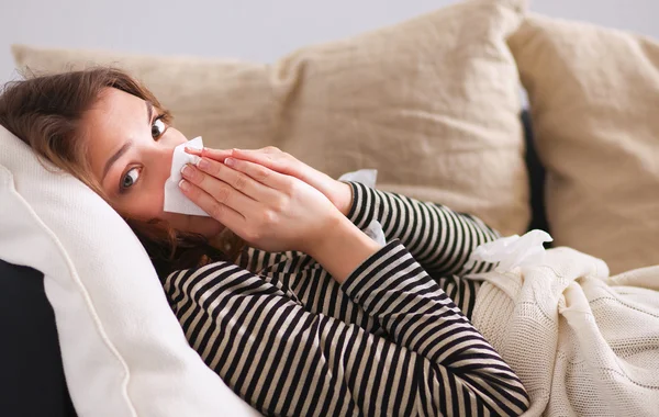 Προσωπογραφία γυναίκας άρρωστος φυσώντας τη μύτη της, ενώ κάθεται στον καναπέ — Φωτογραφία Αρχείου