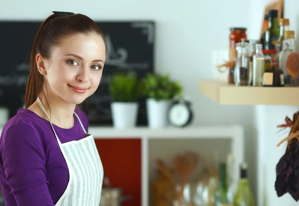 Jeune femme debout dans sa cuisine près du bureau avec des sacs à provisions — Photo