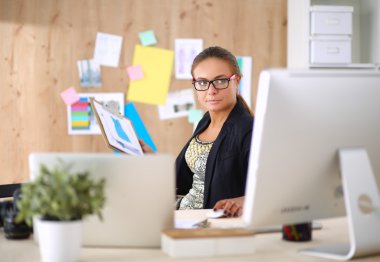 Moda tasarımcıları stüdyoda çalışıyor. Masanın üzerinde oturuyorlar.