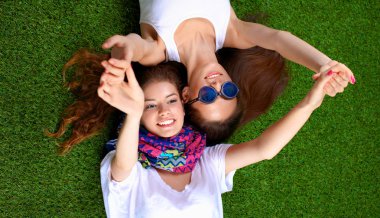 Taze yeşil çimlerin üzerinde yatan iki güzel kız