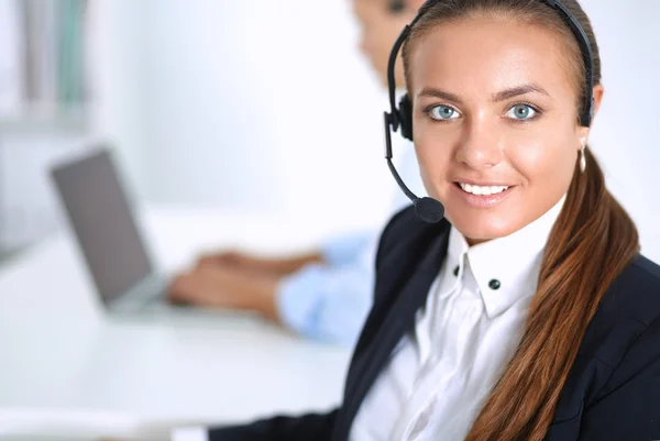 Glückliche Frau trägt Headset und sitzt auf dem Schreibtisch — Stockfoto