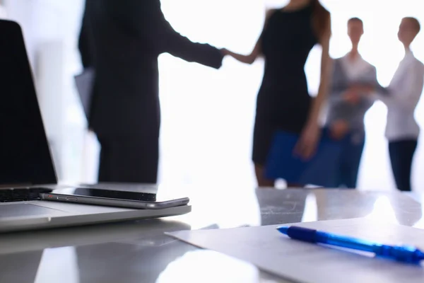 Laptop auf dem Schreibtisch, Geschäftsleute im Hintergrund — Stockfoto