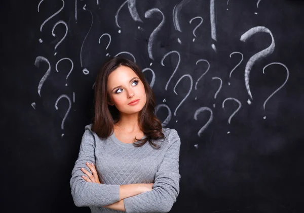 Chica joven con signo de interrogación sobre un fondo gris —  Fotos de Stock