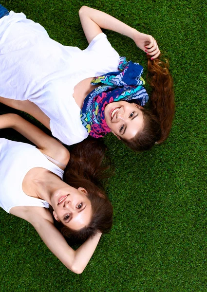 Dvě krásné dívky ležící na čerstvé zelené trávě — Stock fotografie