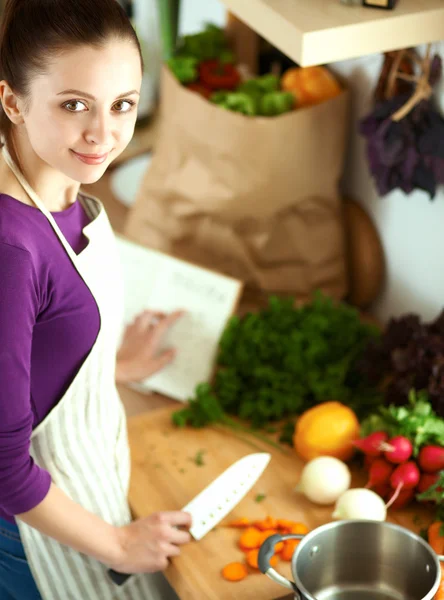 Jovem mulher cortando legumes na cozinha — Fotografia de Stock