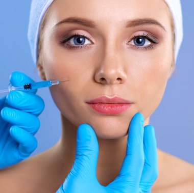 Güzel kadın yüz kozmetik enjeksiyon. Gri arka plan üzerinde izole