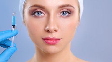 Güzel kadın yüz kozmetik enjeksiyon. Gri arka plan üzerinde izole