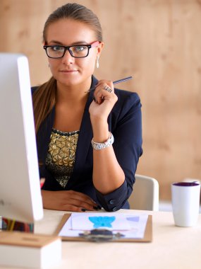 Moda tasarımcıları stüdyoda çalışıyor. Masanın üzerinde oturuyorlar.