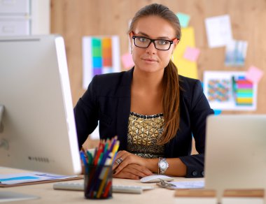 Moda tasarımcıları stüdyoda çalışıyor. Masanın üzerinde oturuyorlar.