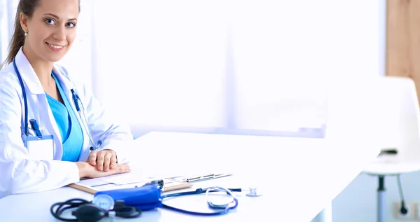 Portrait of young female doctor sitting at desk in hospital — Stock Photo, Image