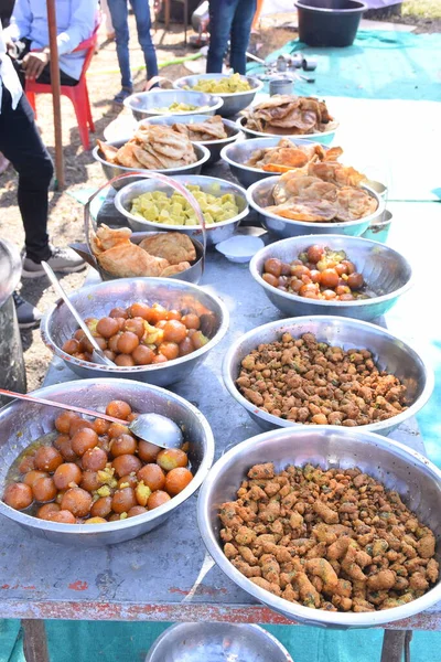 sweets for indian hindu marriage, gulab jamun, cashew katli and fritters placed in steel plate